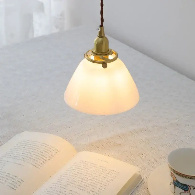 Modern warm-toned glass led pendant lamp with brass fixture and twisted brown cord for kitchen lighting