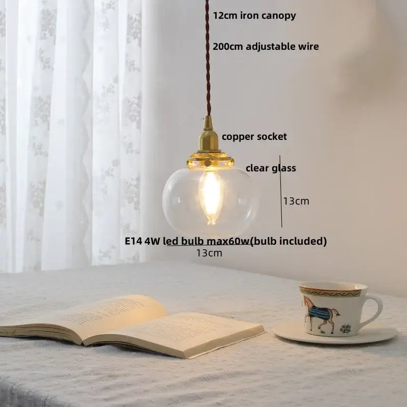 A warm-glowing modern glass led pendant lamp with clear globe, white ceramic, brass copper socket, and iron canopy