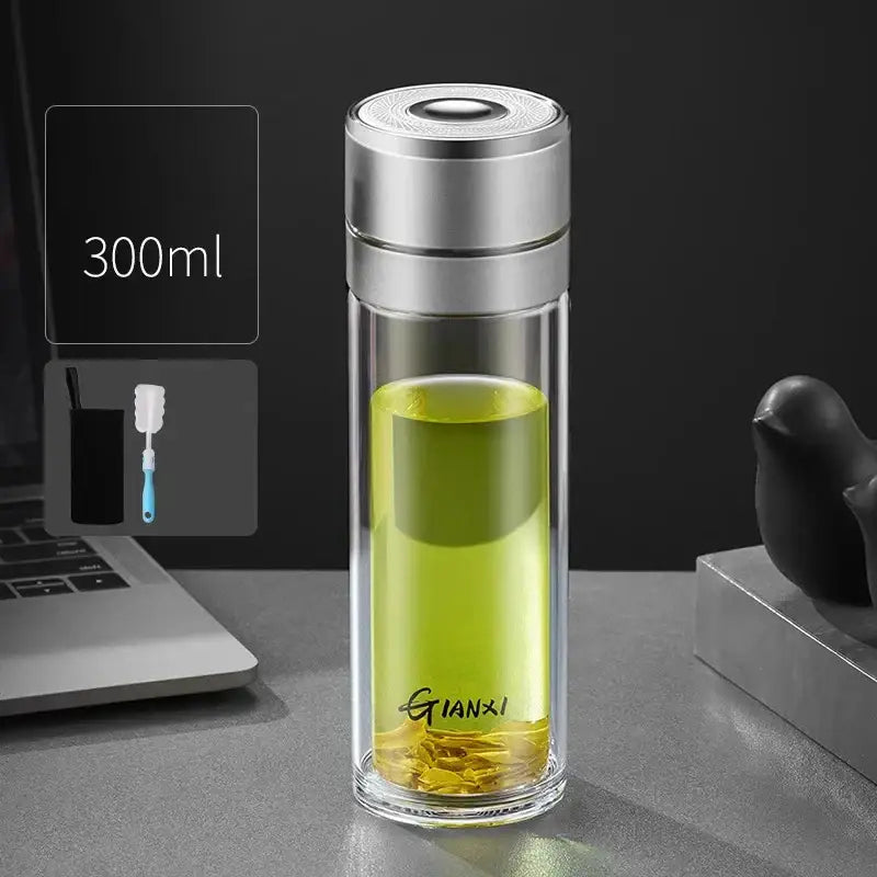 A sleek transparent decorbites insulated glass cup with silver lid filled with green tea leaves and liquid