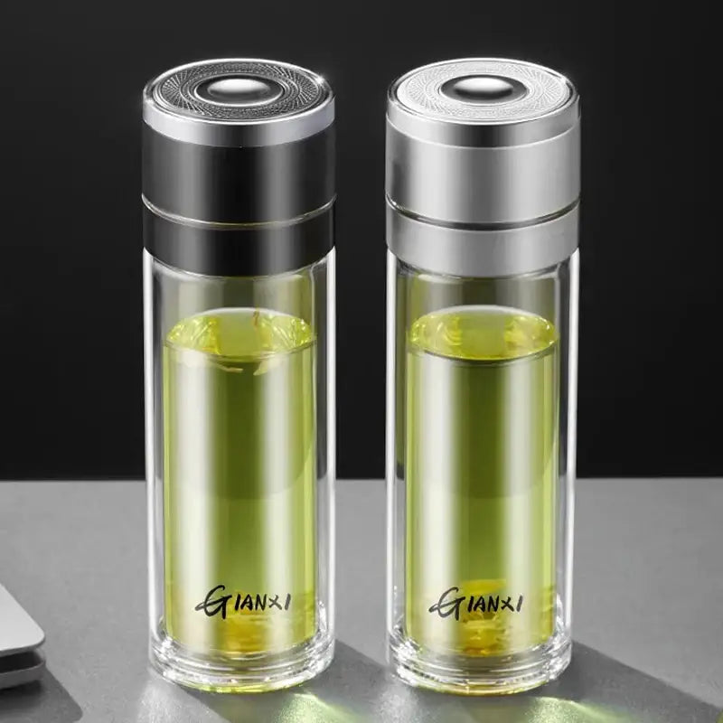 Two transparent decorbites insulated glass cups with silver and black lids containing green liquid