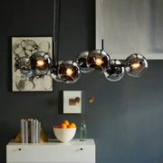 Modern clear smoke glass lighting fixture with black metal frame and warm-toned bulbs for dining room use