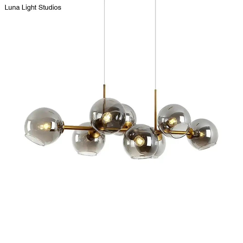 Modern hanging lighting fixture with clear smoke glass spheres and brass arms for dining room black and gold decor