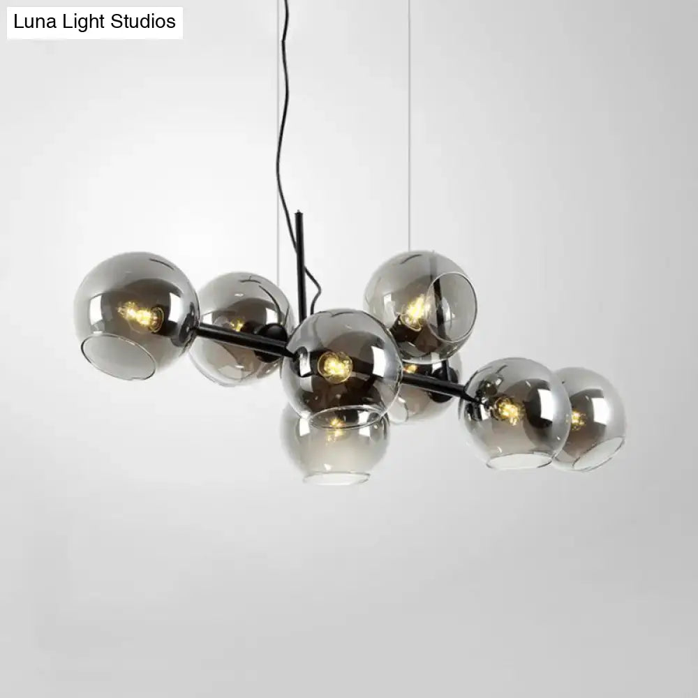 Modern black metal lighting fixture with eight clear smoke glass spheres for dining room use in black and gold finish
