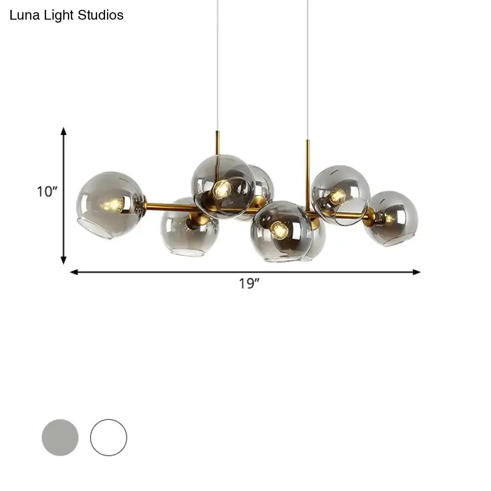 Modern brass-finished lighting fixture with clear smoke glass globe shades in black and gold for dining room use