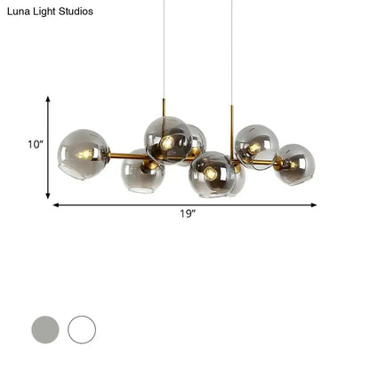 Modern brass-finished lighting fixture with clear smoke glass globe shades in black and gold for dining room use