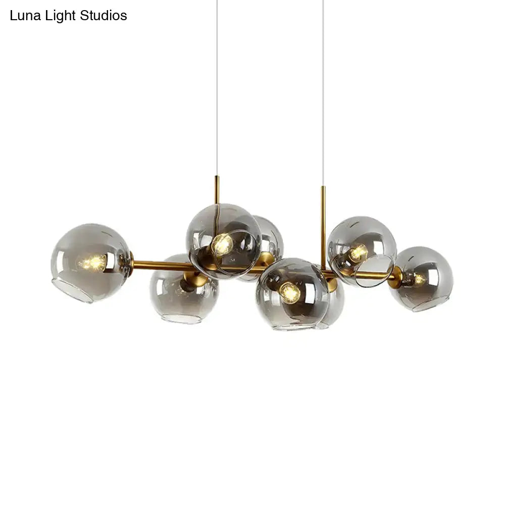 Modern hanging lighting fixture with clear smoke glass spheres and brass-colored metal arms for dining room use
