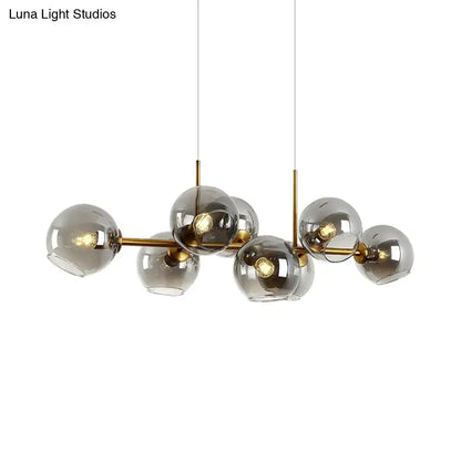 Modern hanging lighting fixture with clear smoke glass spheres and brass-colored metal arms for dining room use