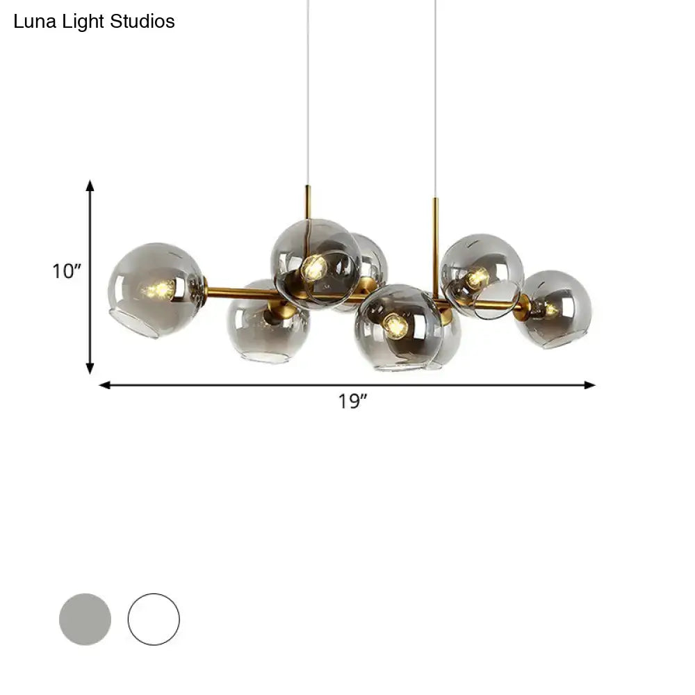 Modern brass-finished lighting fixture with clear smoke glass globe shades in black and gold for dining room use