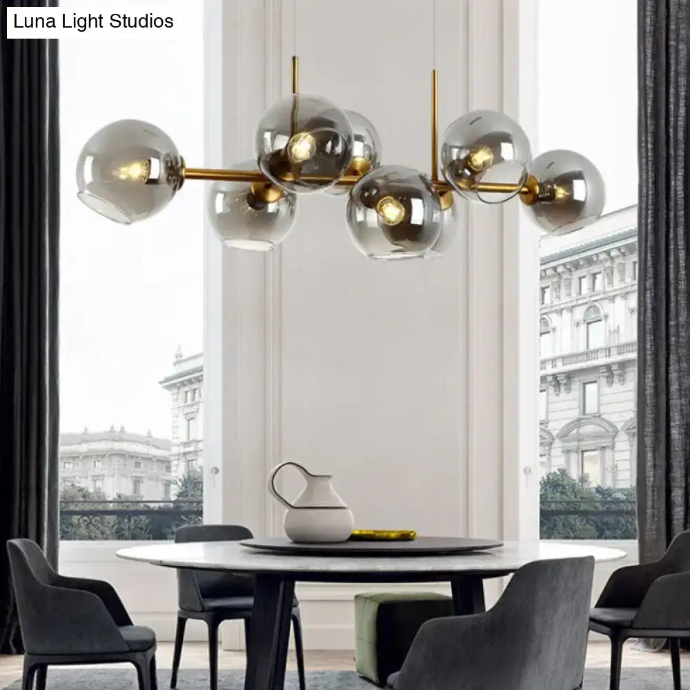 Modern lighting fixture with clear smoke glass globe shades suspended from a black and gold brass bar for dining room