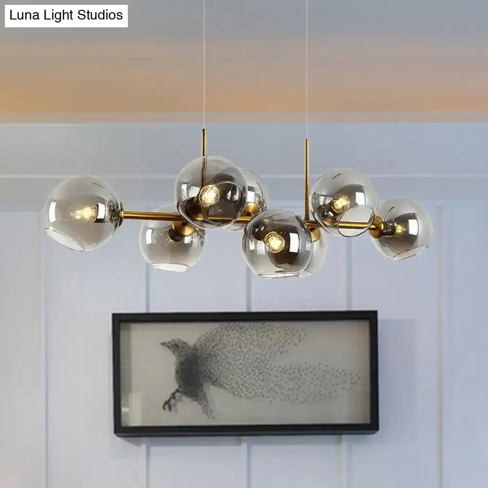 Modern brass lighting fixture with eight clear smoke glass globe shades in black and gold for dining room use