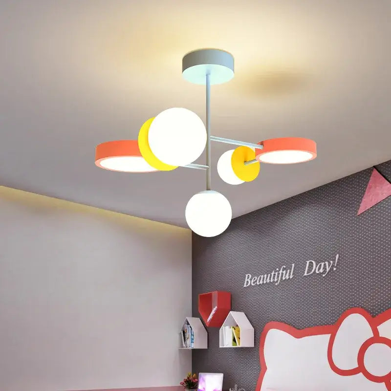 A modern colorful cartoon led chandelier light features a gray stem with white yellow and orange spherical bulbs for kids bedroom