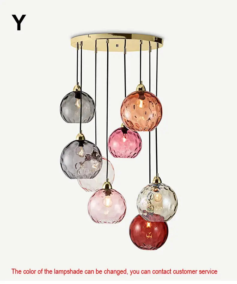 A modern pendant light with decorbites glass ball lustre shades in gray pink and red hanging from gold ceiling mount