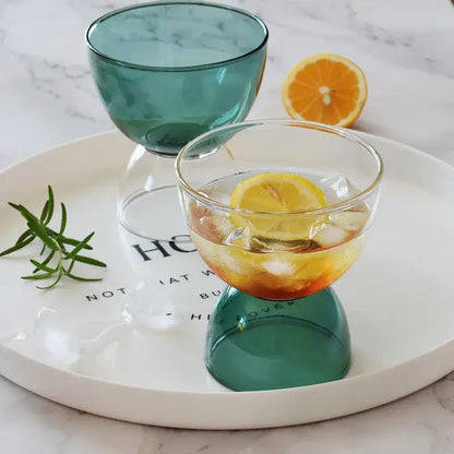 A clear glass dessert ice cream cup with a teal inverted base filled with ice and an orange slice