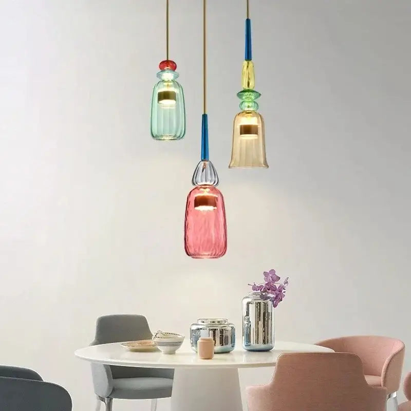 Three colorful glass led pendant chandeliers with gold and blue accents hang above a dining table
