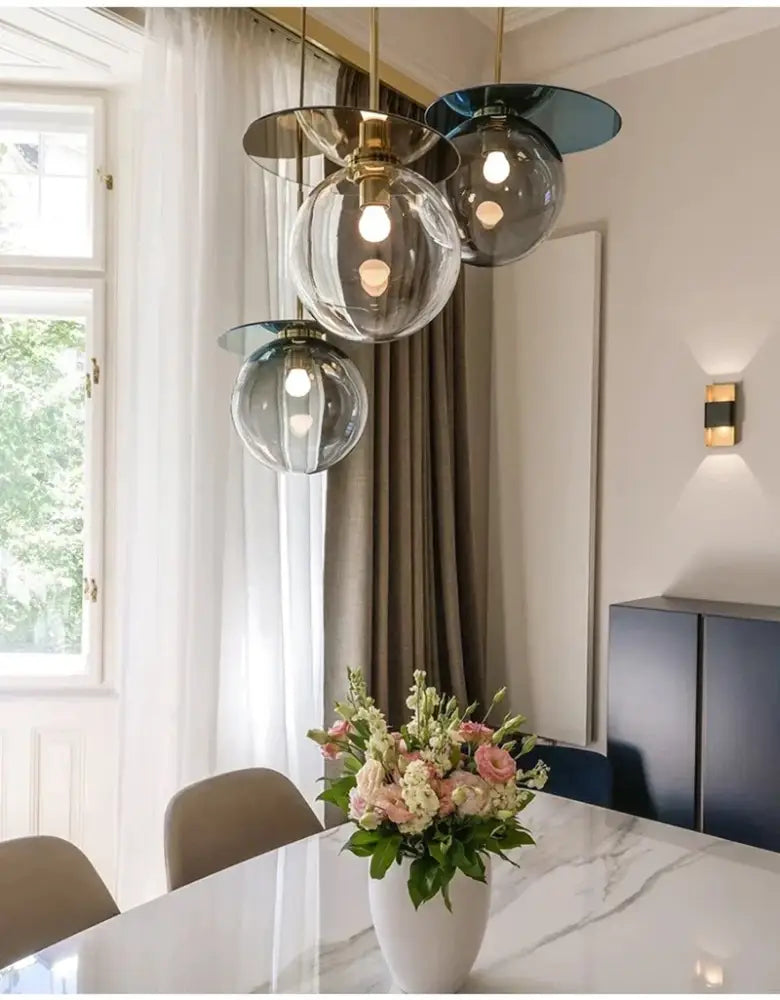 Modern colorful glass metal pendant lamp with brass accents hanging above marble table for dining room decorbites colorful glass