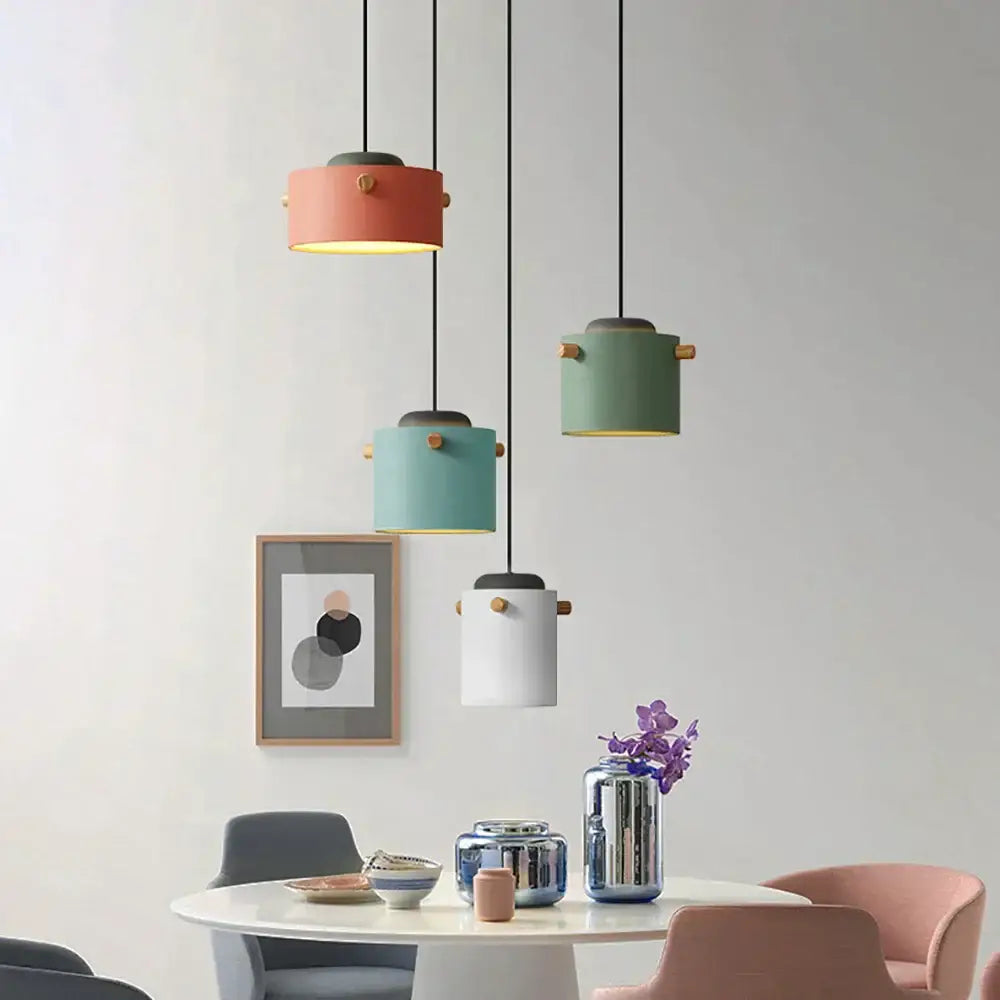 Modern colorful led pendant lights in coral sage green teal and white with brass accents hang above a dining table