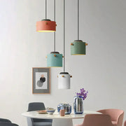 Modern colorful led pendant lights in coral sage green teal and white with brass accents hang above a dining table