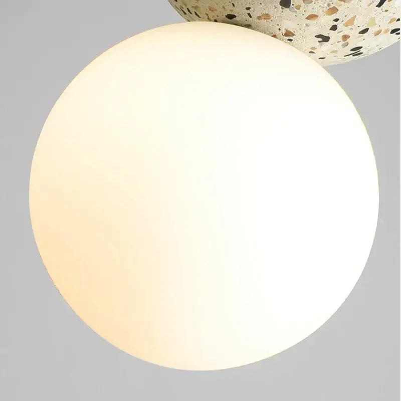 A modern concrete and glass pendant light with an opaque white spherical lampshade and iron finish for dining room use