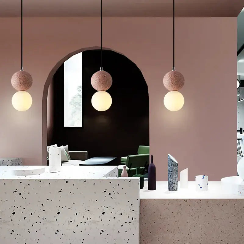 Three-tiered pendant light with pink terrazzo and white glass spheres suspended by black cords iron finish