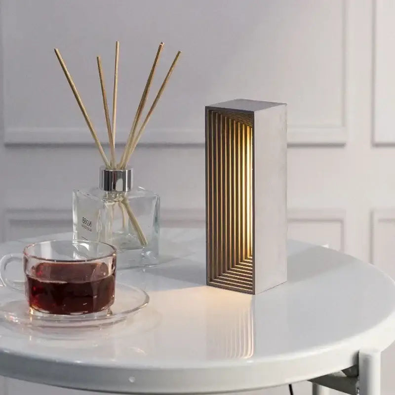 Modern concrete stone table lamp with sleek white exterior and golden wood slats emitting warm light decorbites concrete stone