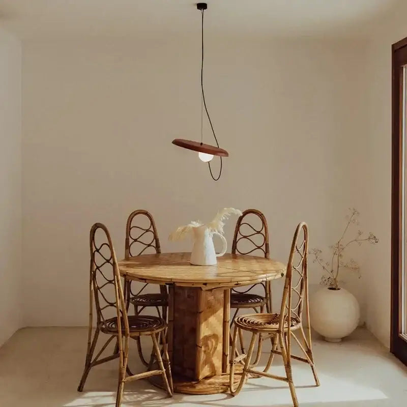 Modern copper and black grid led pendant light with a warm wooden shade hanging above a rustic rattan dining table decorbites grid led