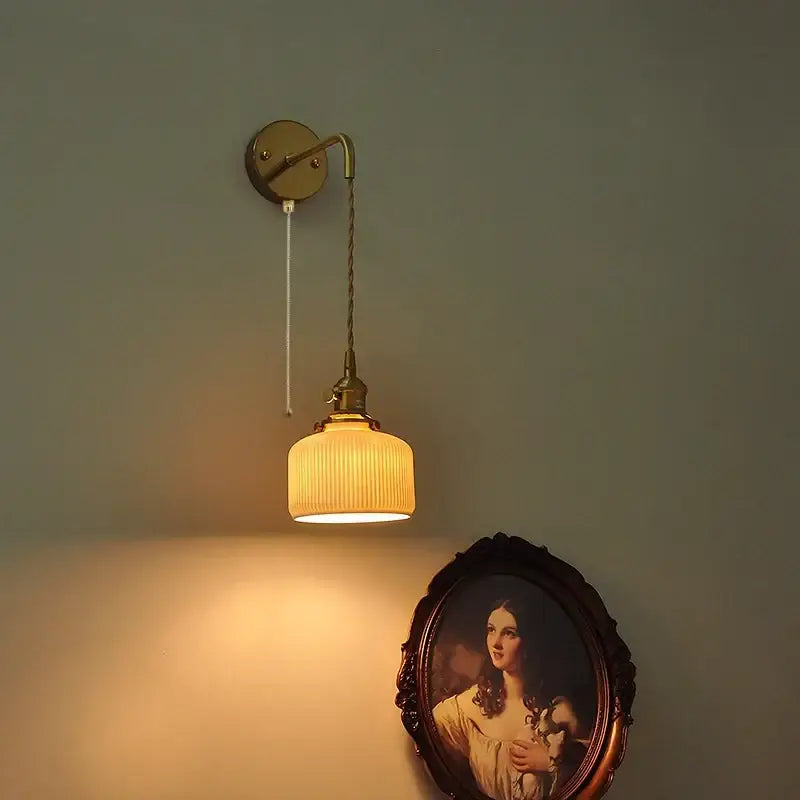 Antique brass wall light fixture with a ribbed warm-toned glass shade for modern bedroom decor