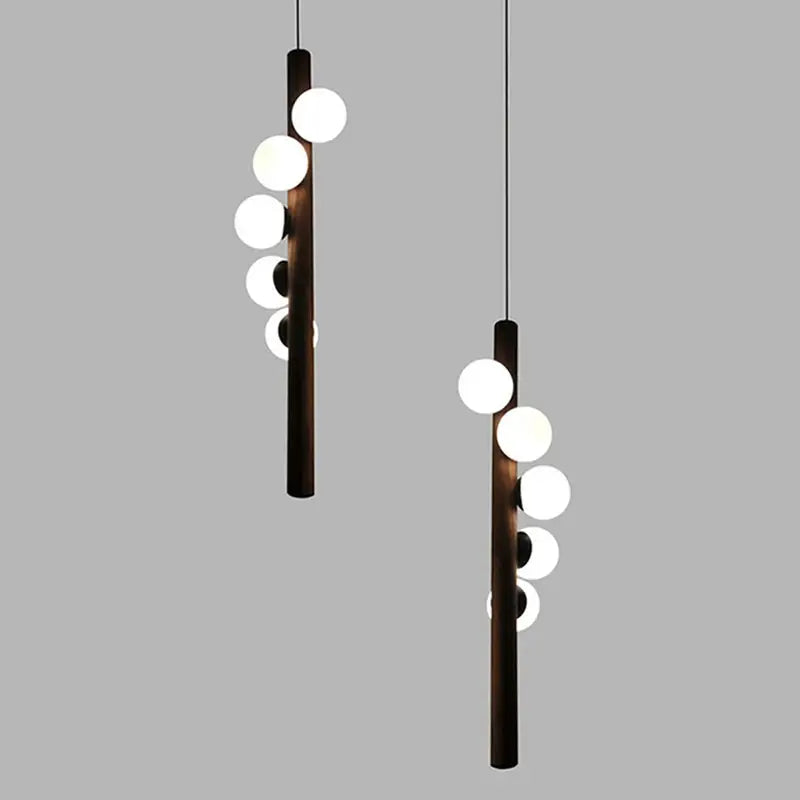 Modern pendant light with dark wooden cylindrical bodies and white spherical bulbs in decorbites burly wood walnut finish