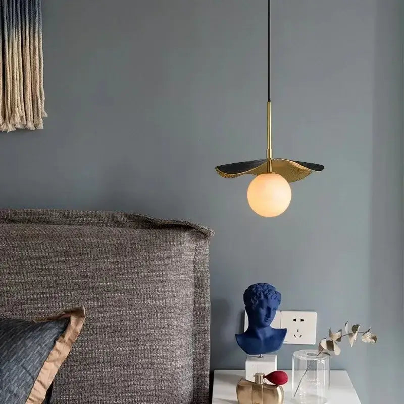 Modern copper bedside chandelier with a gold-toned metal stem and leaf shade featuring an illuminated marble ball bulb decorbites copper bedside
