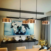 Decorbites contemporary copper ceiling light features four copper-finished metal drum pendant lights above dining table