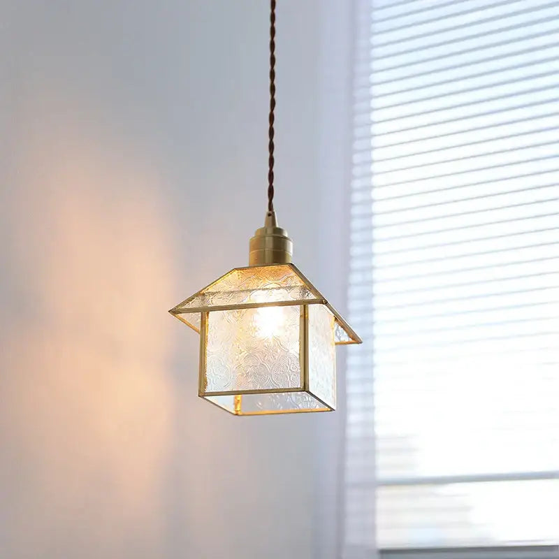 A warm-toned brass-framed modern copper cube glass led pendant light shaped like a small house for bedroom decorbites cube glass