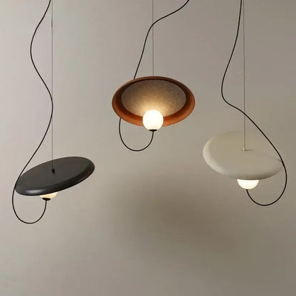 Three modern pendant lights with sleek curved black cords and matte black, warm brown, off-white decorbites grid color shades