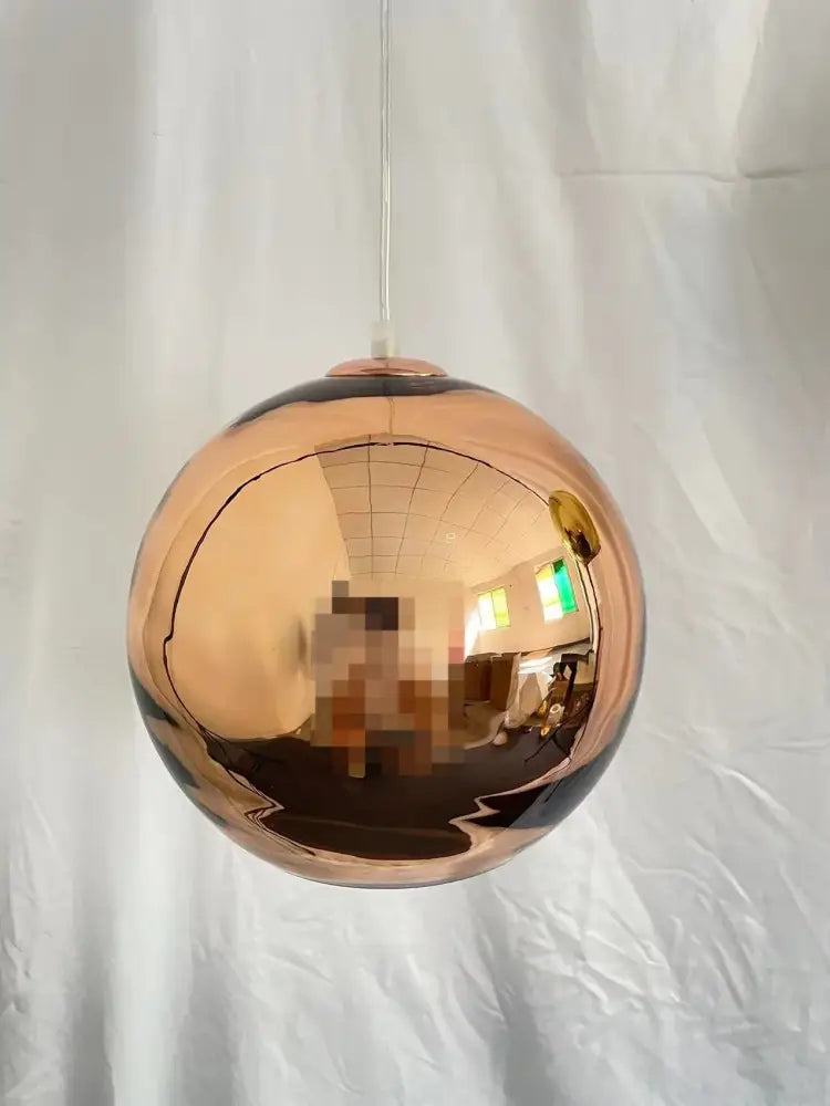 A sleek spherical copper-colored pendant light with a reflective finish perfect for modern kitchen decorbites glass balls pendant
