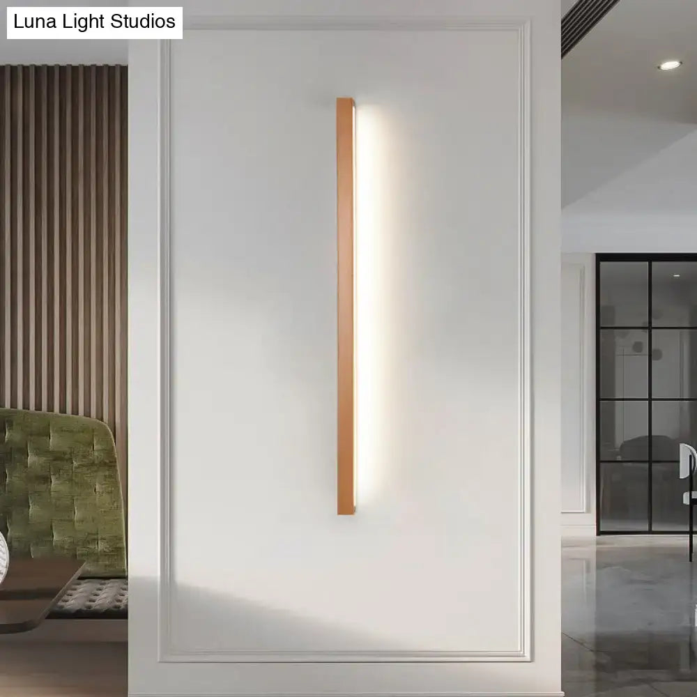 A modern copper linear shaped wall sconce with a warm wooden frame and LED strip for living room lighting