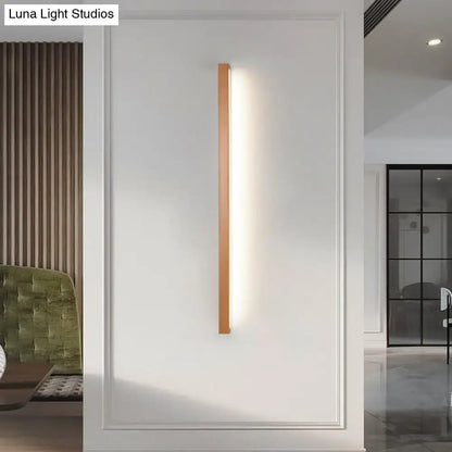 A modern copper linear shaped wall sconce with a warm wooden frame and LED strip for living room lighting