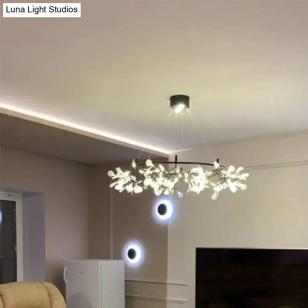 A modern copper tree branch pendant light with black circular base and white glowing flower lights for dining room