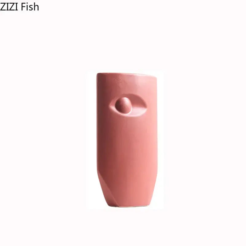 A sleek matte pink decorbites ceramic vase with a minimalist abstract eye design for modern living room decor