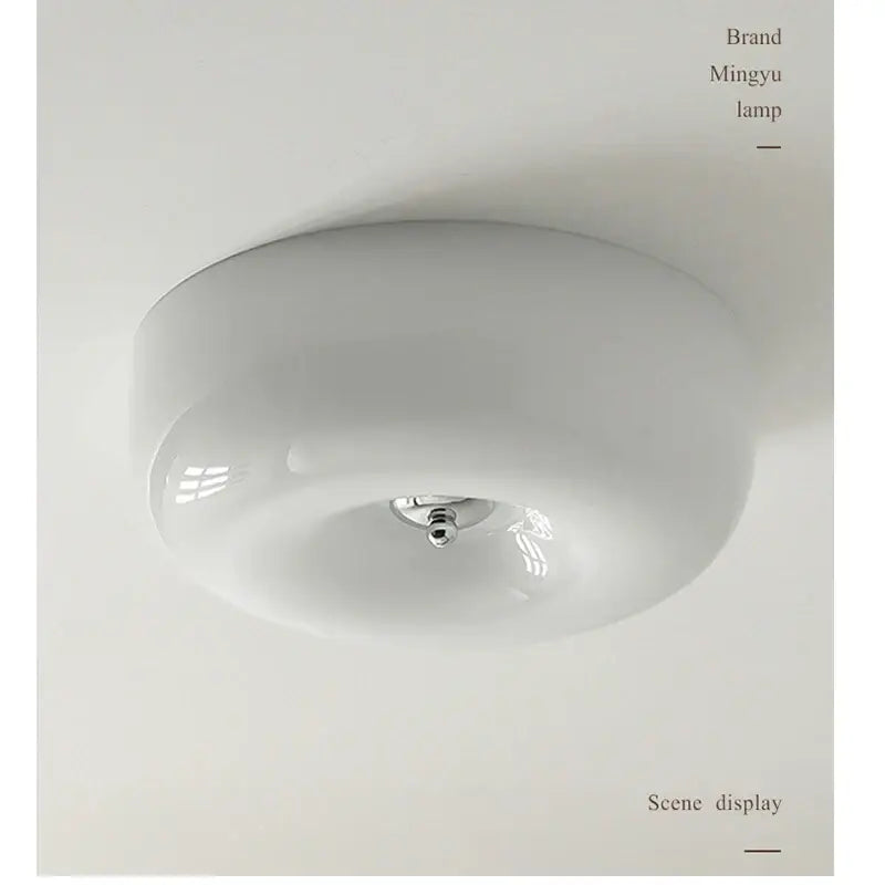 A sleek minimalist cream bauhaus style ceramic ceiling lamp with a rounded glass dome and polished chrome fixture