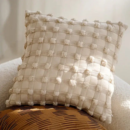 Cream-colored decorbites brown coffee pillowcase with quilted textured grid pattern and fluffy pom-poms for living room decor
