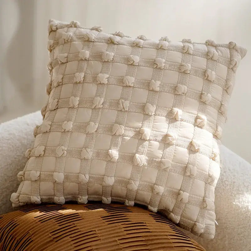 Cream-colored decorbites brown coffee pillowcase with quilted textured grid pattern and fluffy pom-poms for living room decor