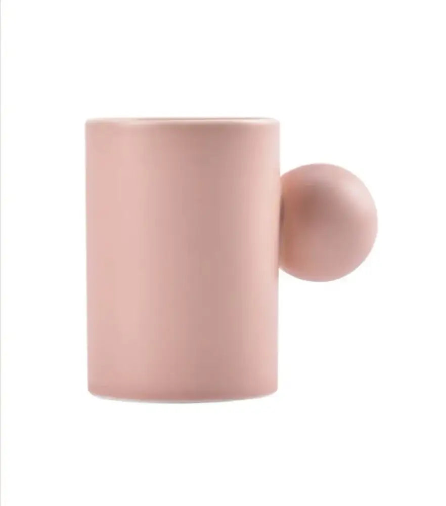 A matte pink ceramic cup with a spherical handle from the modern cream ceramic cup and saucer set decorbites cotton candy