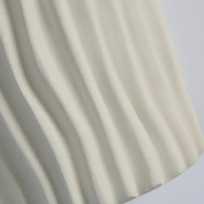 Modern cream ceramic ridged led wall lamp featuring soft pleated fabric with flowing vertical folds for bedroom sconce