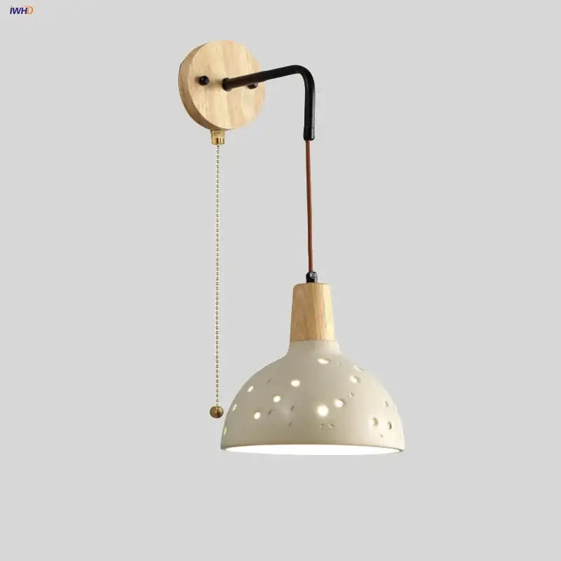 Modern cream ceramic wall lamp with wooden arm and pull chain switch featuring circular cutouts for bedroom lighting