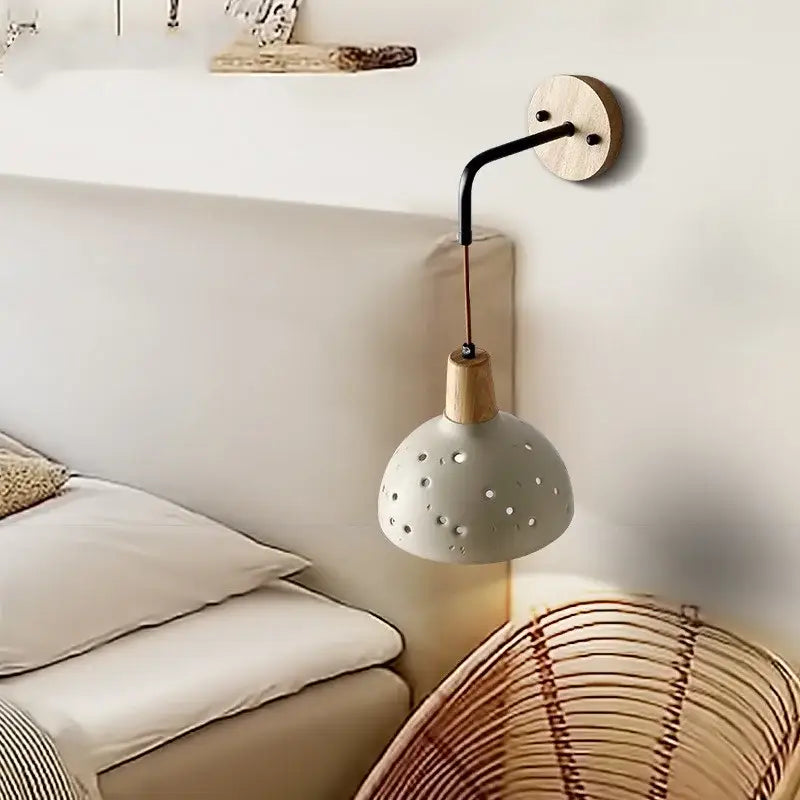 Modern cream ceramic wall lamp with pull chain switch featuring a matte gray perforated shade on a light wood base