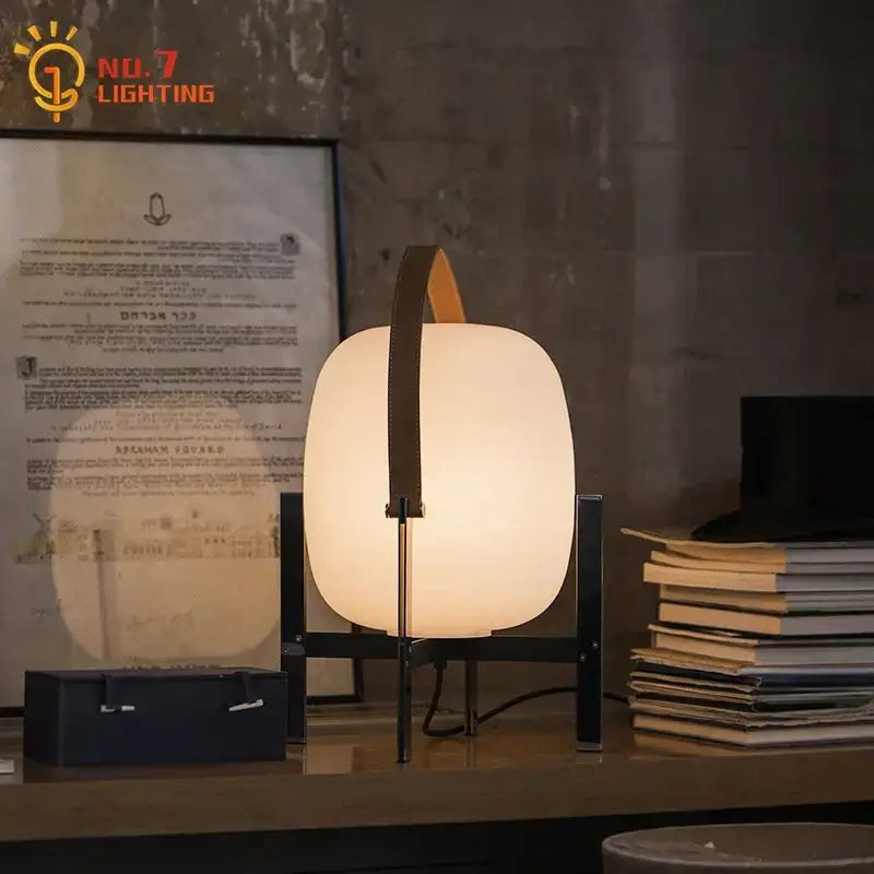 Modern cream designer metal glass table lamp with frosted body, dark frame, and orange leather handle for decorbites decor