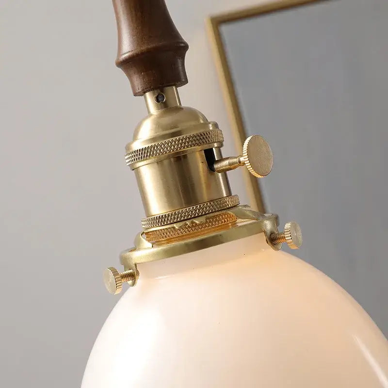Antique brass-finished industrial pendant light with dark wood handle and frosted white glass copper led shade for dining room