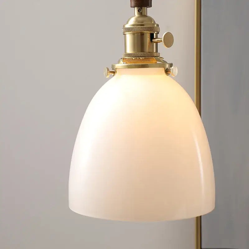 A warm off-white glass copper led pendant light with brass fixture and adjustable knobs for modern dining rooms