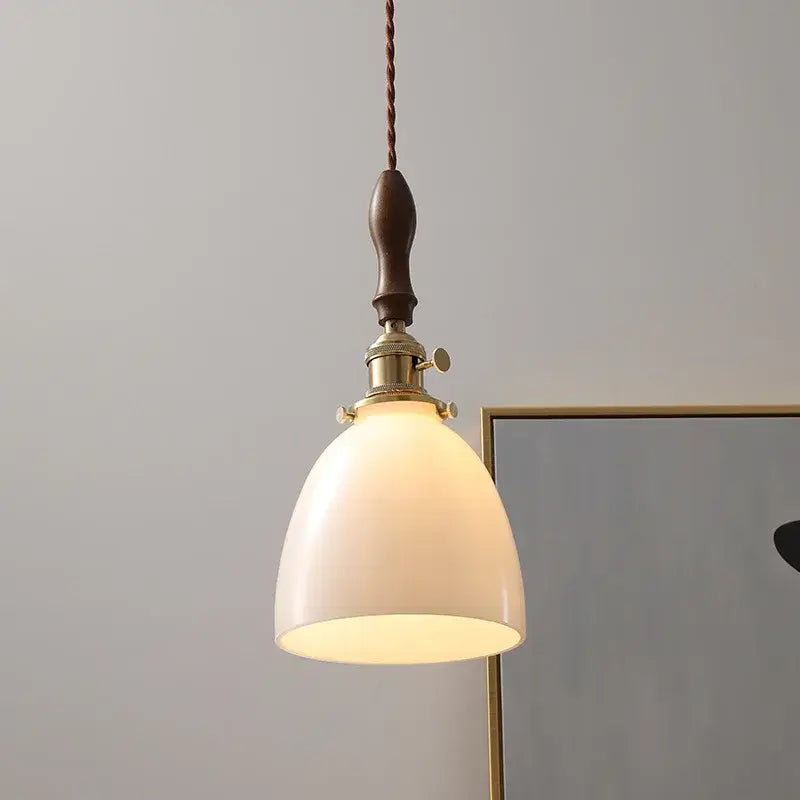 A warm-toned modern cream glass copper led pendant light with brass fixture and dark wood handle for dining room