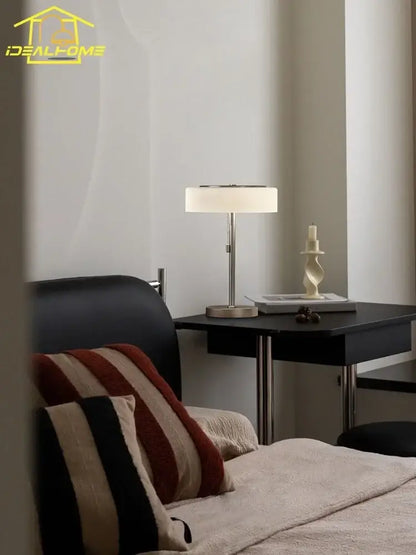 Modern cream glass table lamp with a sleek silver metal base and off-white fabric shade for bedroom decorbites cream glass