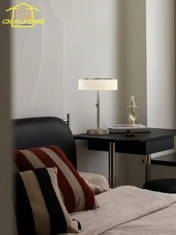 Modern cream glass table lamp with a sleek silver metal base and off-white fabric shade for bedroom decorbites cream glass