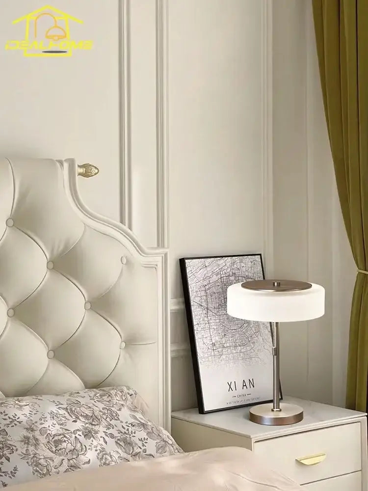 A sleek cream glass table lamp with a brushed metal base and circular shade for bedroom decorbites decor